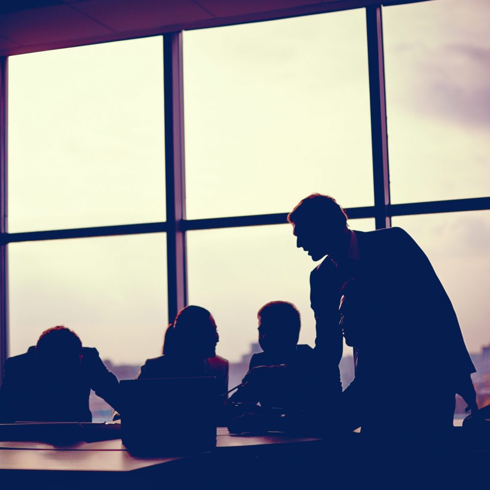 Several colleagues communicating in office against window